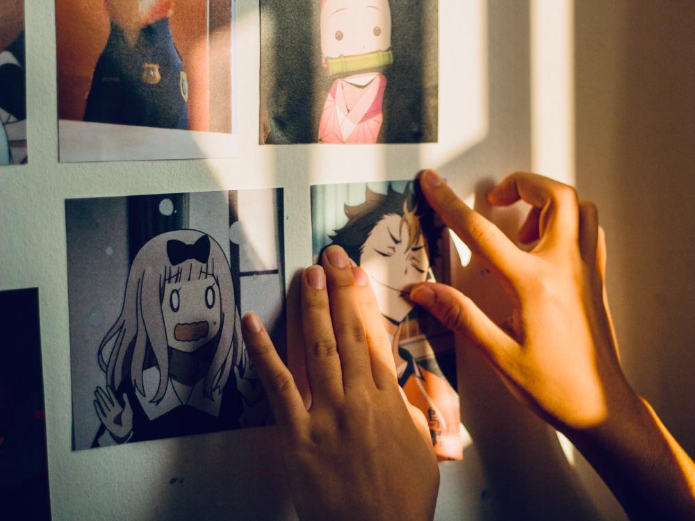 A photo of a hand holding cards on an anime storyboard.